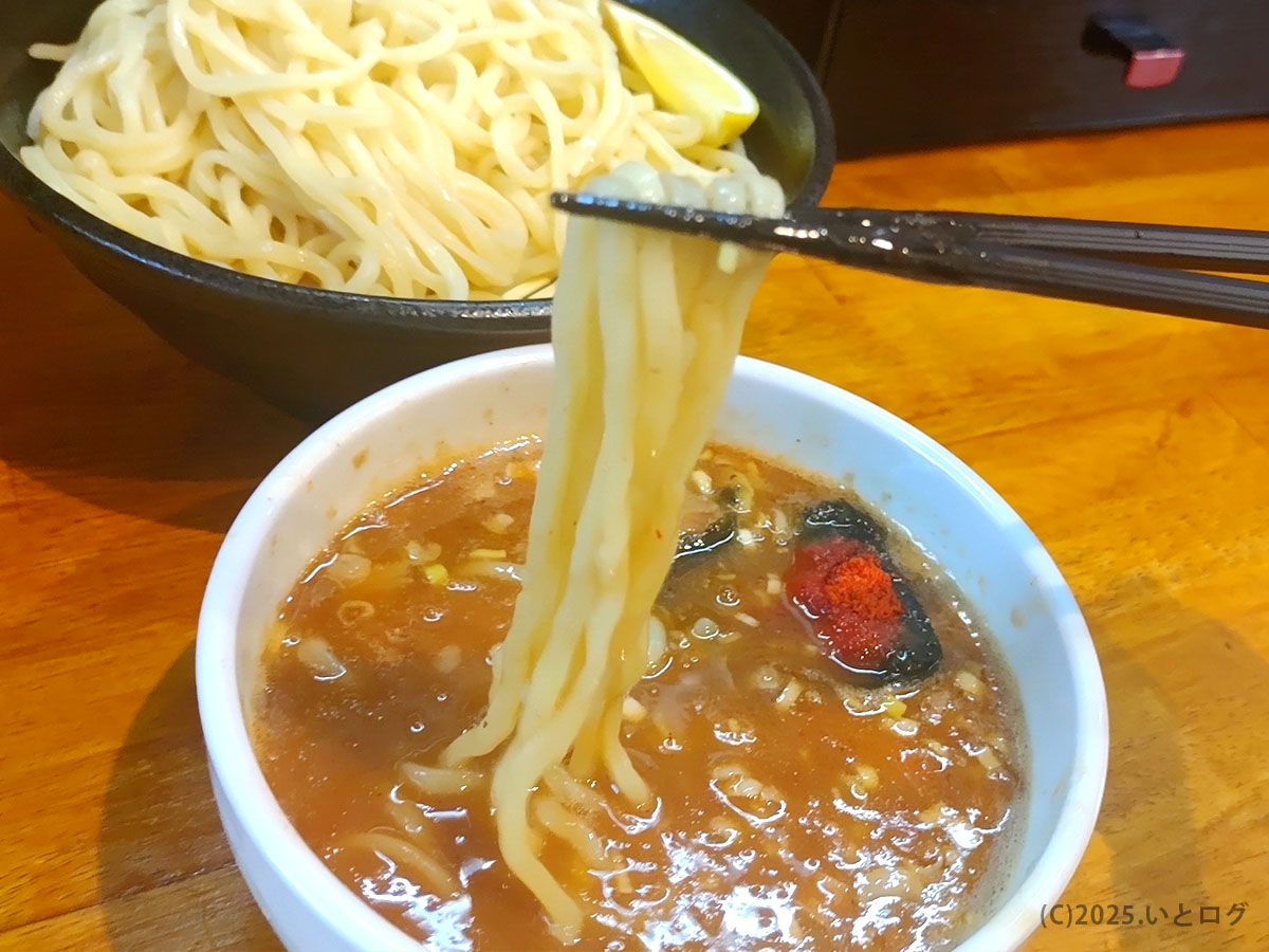 レモンを添えた冷たい中太麺をつけ汁にくぐらせてリフトアップ—麺屋 おう道の魚介つけ麺
