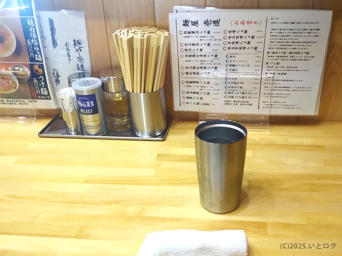 卓上に整列した胡椒や酢などの基本調味料とステンレスカップ。山梨ラーメン24時間探索派にも頼もしい味変セット