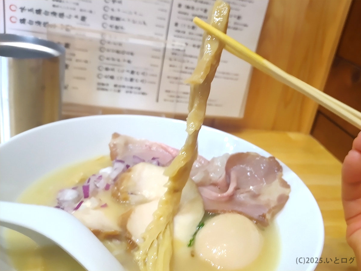 波打つ極太メンマを箸でリフトアップ。鶏白湯に映えるご当地トッピングが、甲斐市ラーメン新店舗の高評価ぶりを物語る