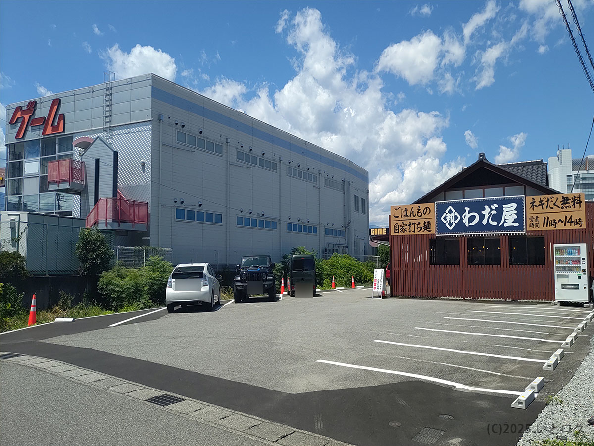 甲府市の中華そば わだ屋 甲府昭和分店の外観と広い駐車場。青空の下、分店の場所がわかる全景