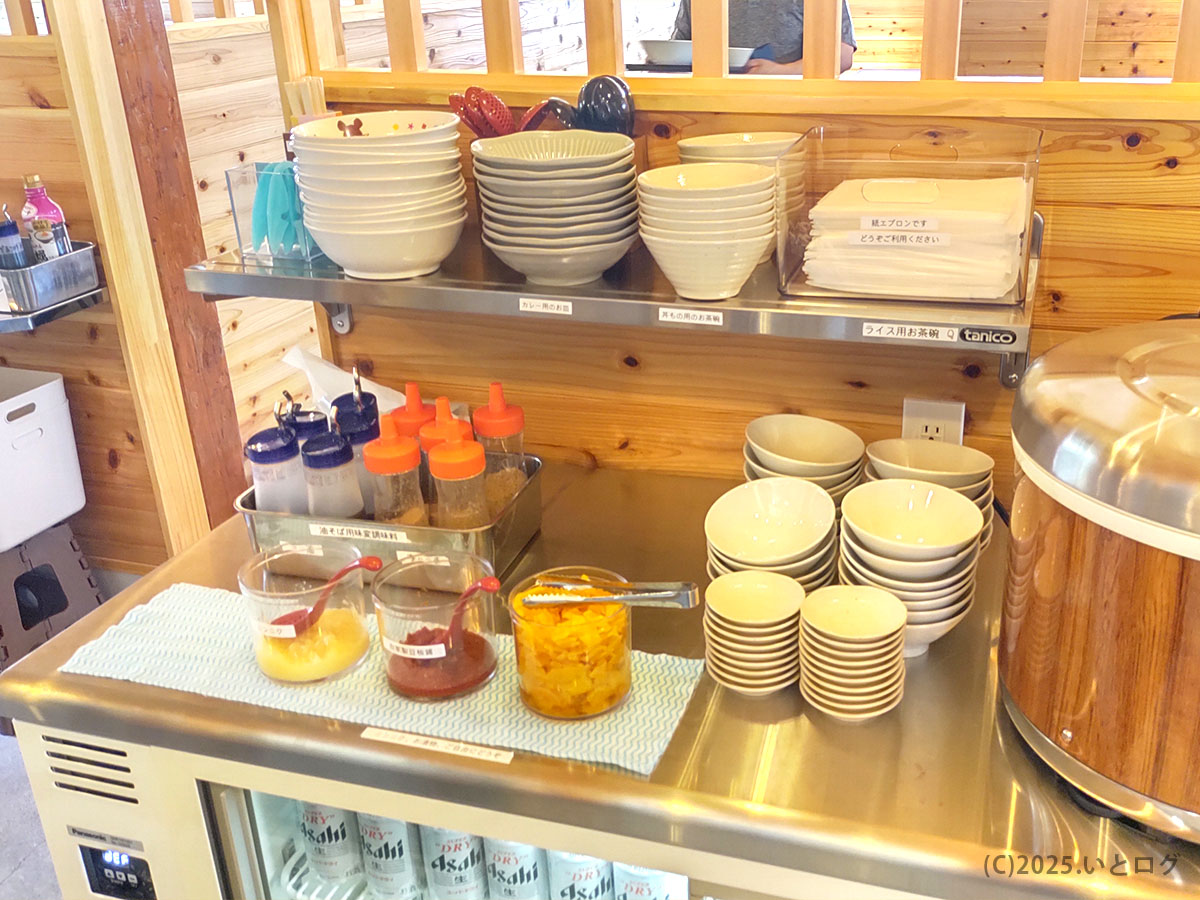 セルフの調味料と小鉢コーナー。ライス用お茶碗や炊飯ジャーが並ぶ、わだ屋 甲府昭和分店のサービス台