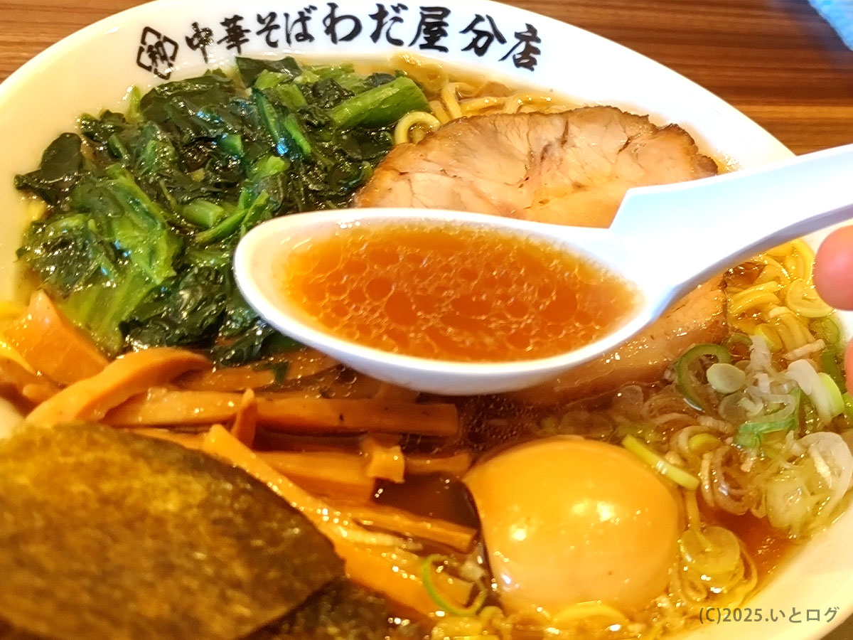 「中華そば」の透きとおる醤油スープをレンゲで。丼の縁には“わだ屋分店”のロゴが入る