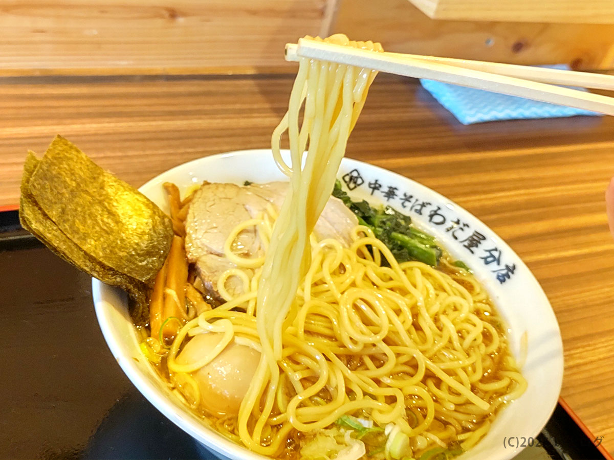 自家打ち風の中細麺を箸上げ。丼縁の「わだ屋分店」ロゴが見える、甲府市のわだ屋 甲府昭和分店の中華そば
