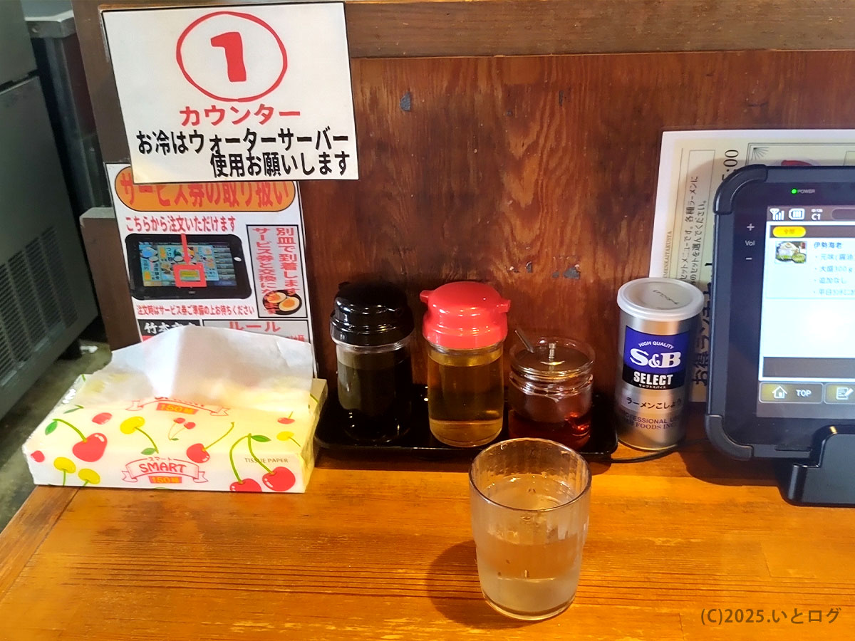 竹本商店 秋田のカウンター席に並ぶ卓上調味料とウォーターサーバー