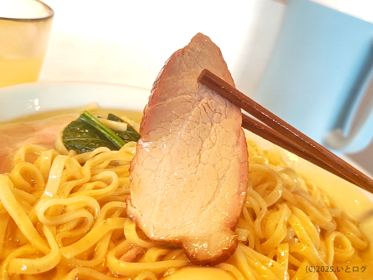 青森中華そばオールウェイズの中華そばにのるチャーシューを箸で持ち上げた様子。しっとりとした肉質が伝わる