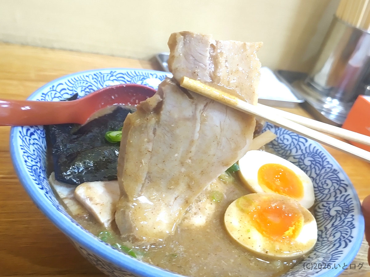 ひかり食堂のラーメンにのるチャーシューを箸で持ち上げた様子