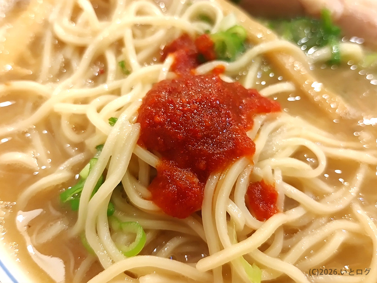 久留米とんこつラーメン松山分校のラーメンに辛味調味料を加えた麺のアップ。とんこつスープの変化を楽しむ一杯