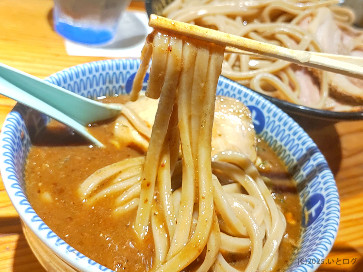 Wez Noodles(中華蕎麦うゑず/山梨県昭和町)の濃厚つけ麺。太めの麺を箸で持ち上げ、魚介系つけダレに潜らせている様子。うえずメニューの人気つけ麺で、ラーメン予約やLINE受付方法を調べて訪れた人が味わう定番スタイル。麺の質感や濃度が分かる近接カット。