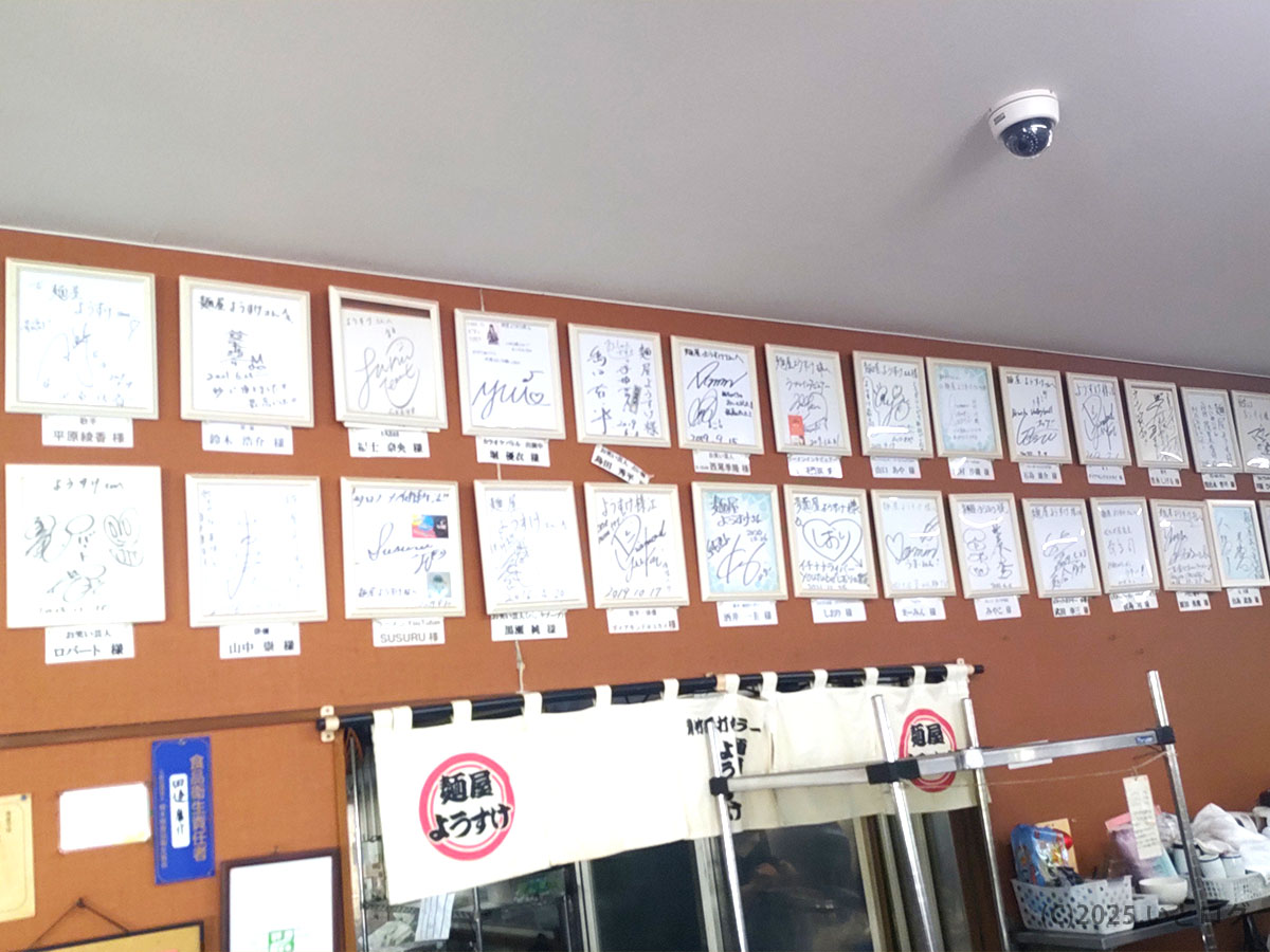 店内奥の壁一面に飾られた有名人のサイン色紙。麺屋ようすけ 店舗の人気ぶりが伝わり、 “事故物件” の噂を笑い飛ばす賑わいを証明。