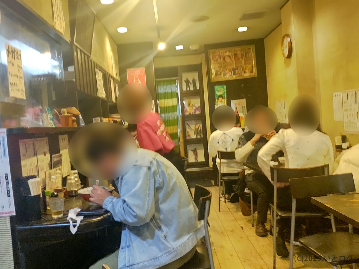 夜の製麺処 蔵木 本店の店内。カウンターとテーブルが満席になり、客が〈蔵木 ラーメン〉や牛モツつけ麺をすする活気があふれる高知のラーメン空間。