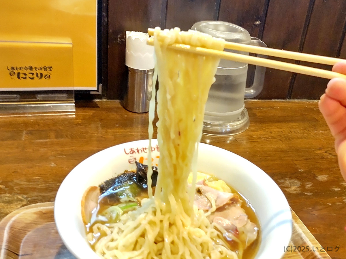 湯河原・しあわせ中華そば食堂にこりの縮れ麺をリフトする瞬間。湯気とともに香り立つ熱々の中華そば。