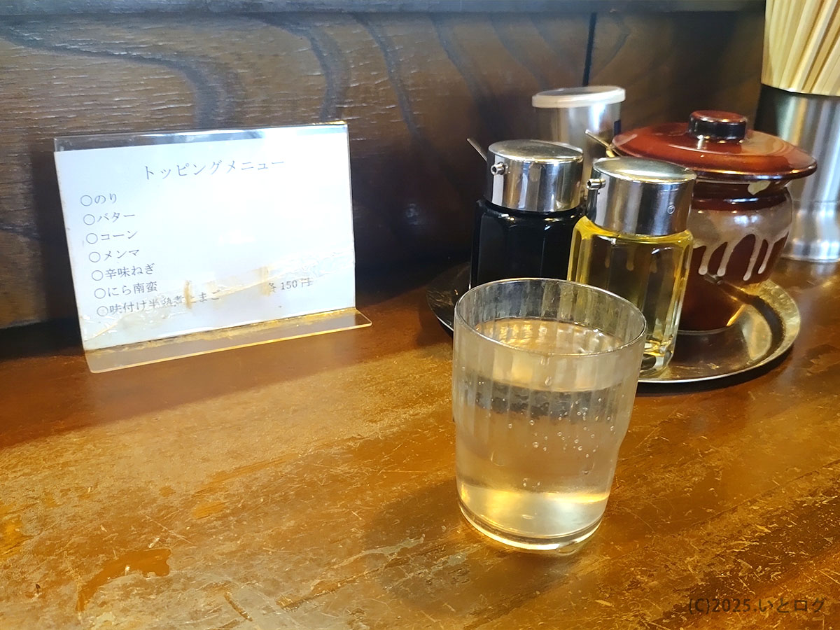 ラーメンショップ チャイナタウンのカウンターに置かれた卓上調味料と水、落ち着いた店内の様子