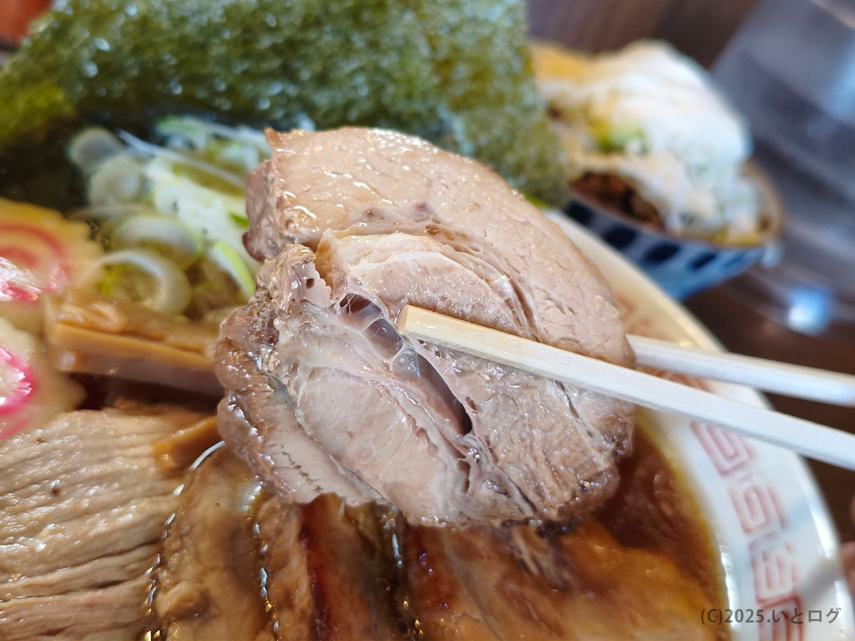 三角屋 暖のチャーシュー、繊維感が伝わる大ぶりカットを箸で持ち上げた様子