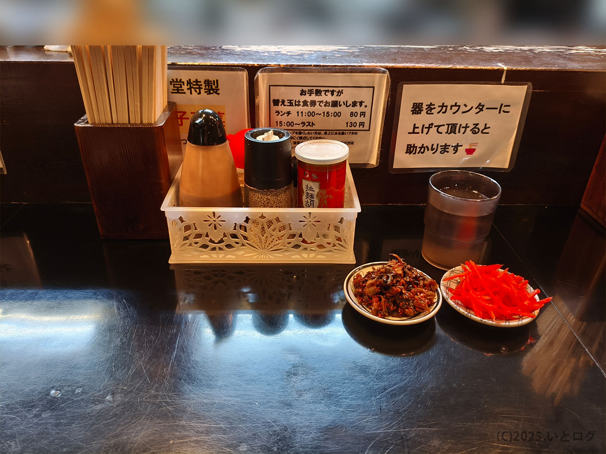 六角堂のカウンター席に置かれた調味料と取り皿の様子、甲府の豚骨ラーメン店らしいシンプルな卓上