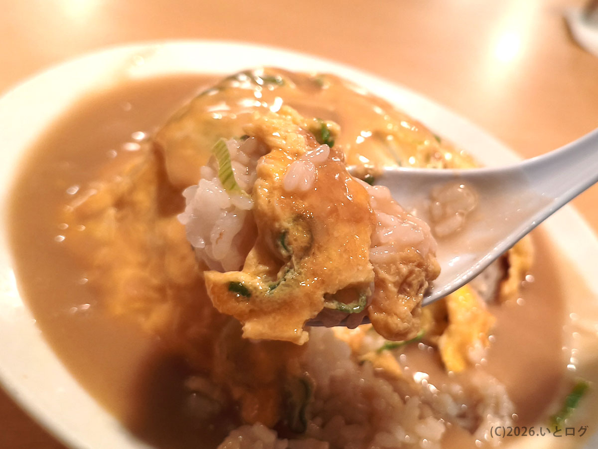 トンテキ屋ちゃん四日市店の天津飯をスプーンですくったところ。餡がたっぷりかかった一皿