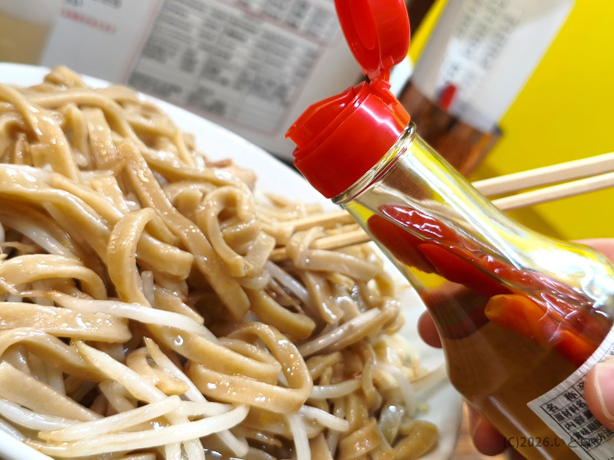 コーレーグースで味変する様子（沖縄ラーメン×二郎系の特徴）