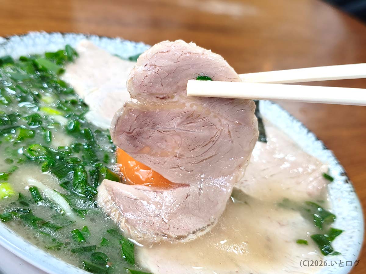 幸陽閣 チャーシューメンのやわらかいチャーシューを箸で持ち上げた様子 生卵入りラーメンの人気メニュー