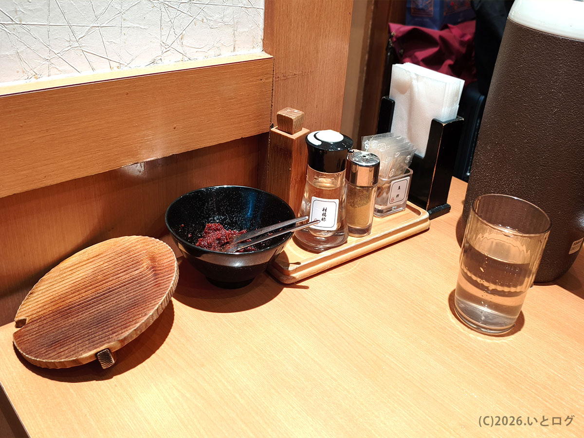 六厘舎 東京駅のカウンターに置かれた卓上調味料と水。つけ麺の味変に使われる定番アイテム