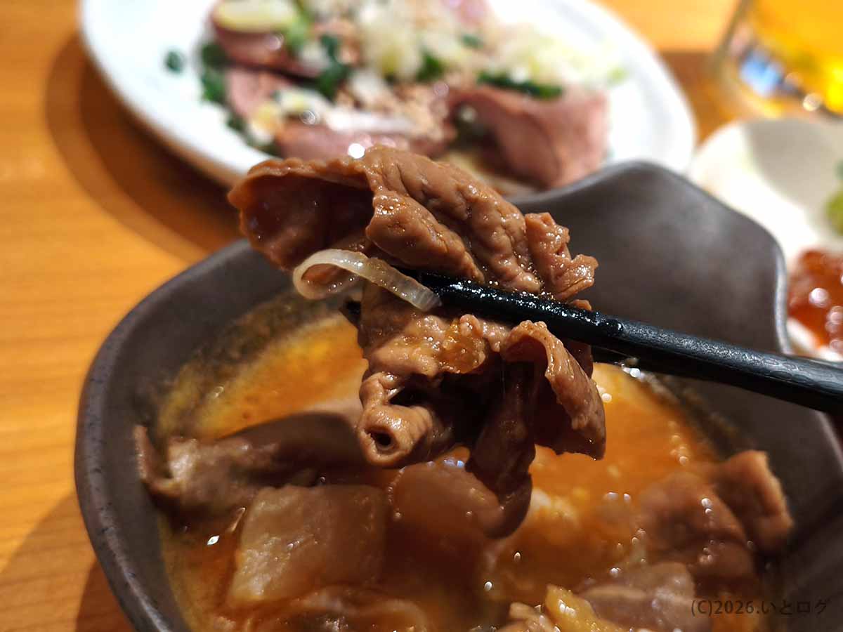 立飲みカドクラ名物の牛スジ煮込みを箸で持ち上げた様子