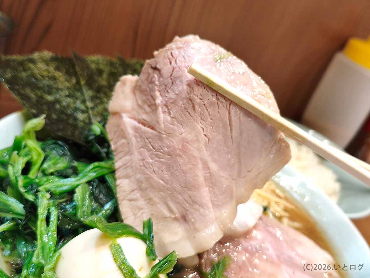 武蔵家 秋津店のチャーシューを箸で持ち上げた様子。しっとり柔らかな豚肉が特徴