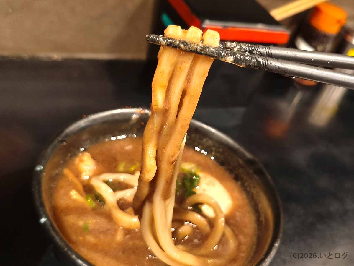 つけ麺 無心の極太麺を濃厚豚骨のつけ汁にくぐらせて持ち上げた様子