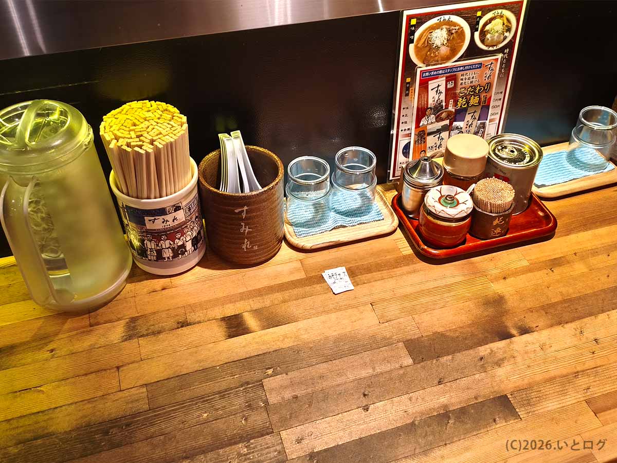 すみれ 横浜店のカウンター席に置かれた卓上調味料や箸、水差し。野毛で札幌味噌ラーメンを味わえる人気店の店内風景