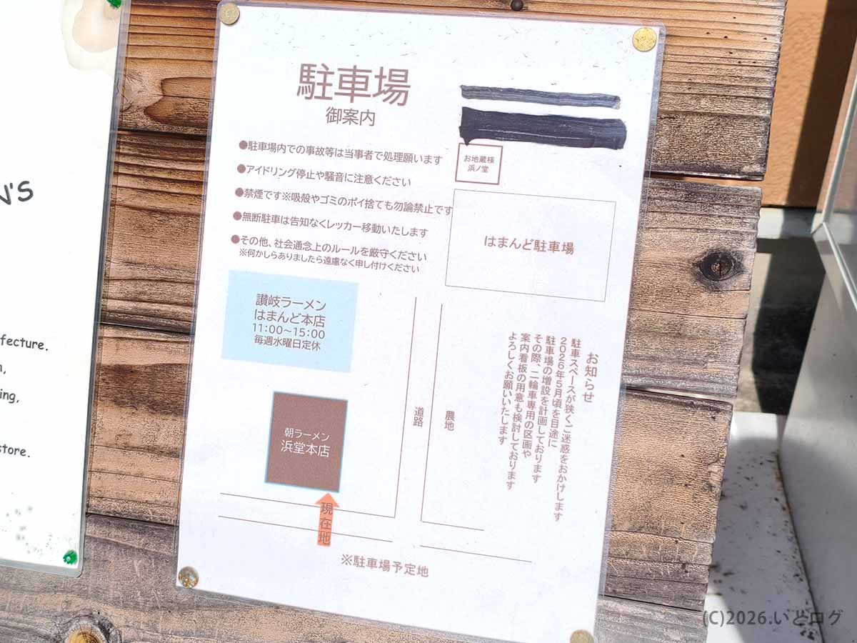 香川県三豊市にある讃岐ラーメン はまんど本店の駐車場案内。店舗前の掲示板に、はまんど駐車場と朝ラーメン浜堂本店の位置が案内されている。