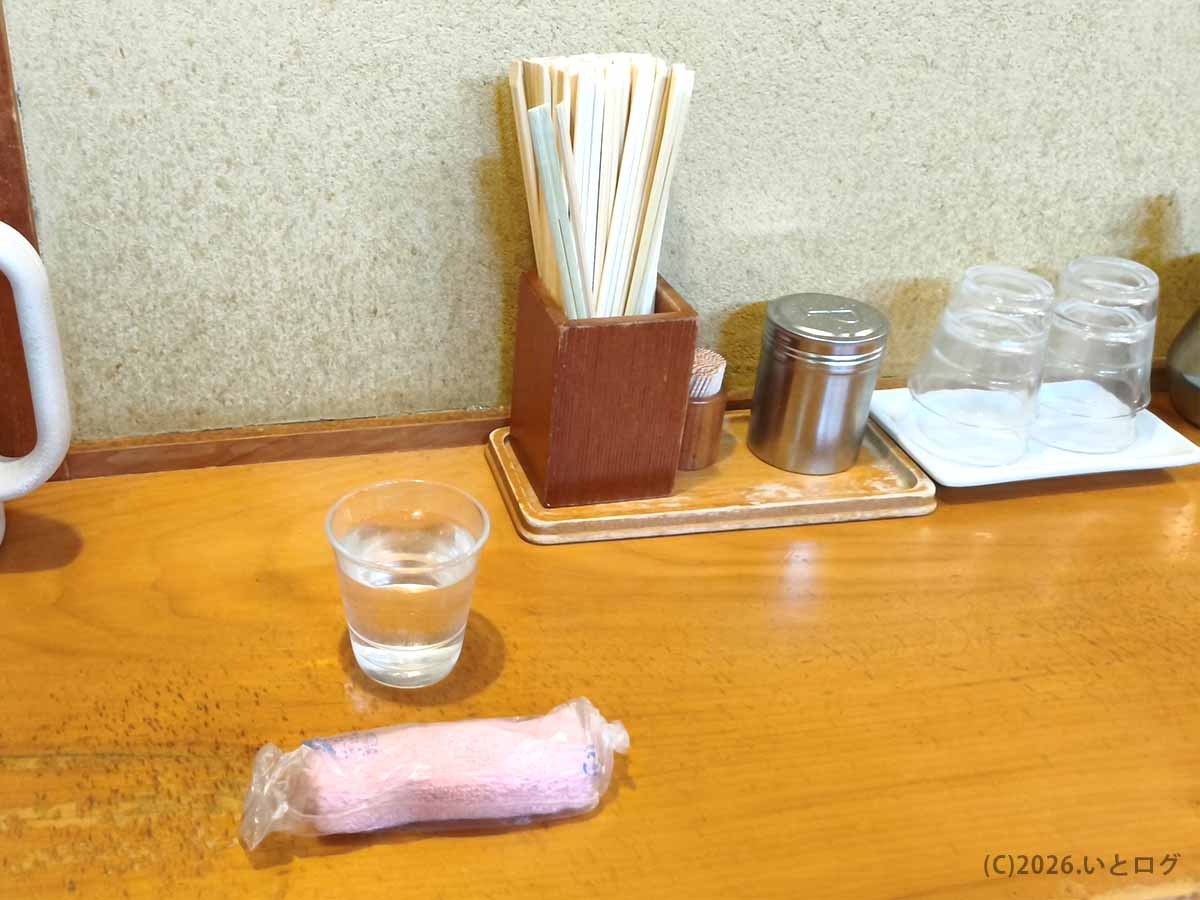 讃岐ラーメン はまんど本店のカウンター席。木目のカウンターに水、箸、調味料、コップが並び、落ち着いた店内の雰囲気が伝わる。