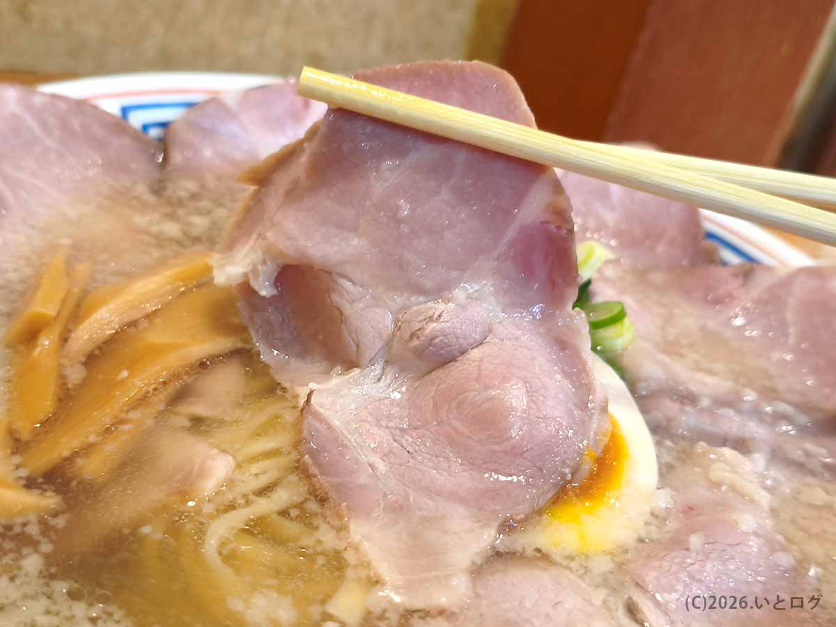 讃岐ラーメン はまんどのチャーシューを箸で持ち上げた様子。薄切りながら大きめのチャーシューが、丼の縁を覆うように盛り付けられている。