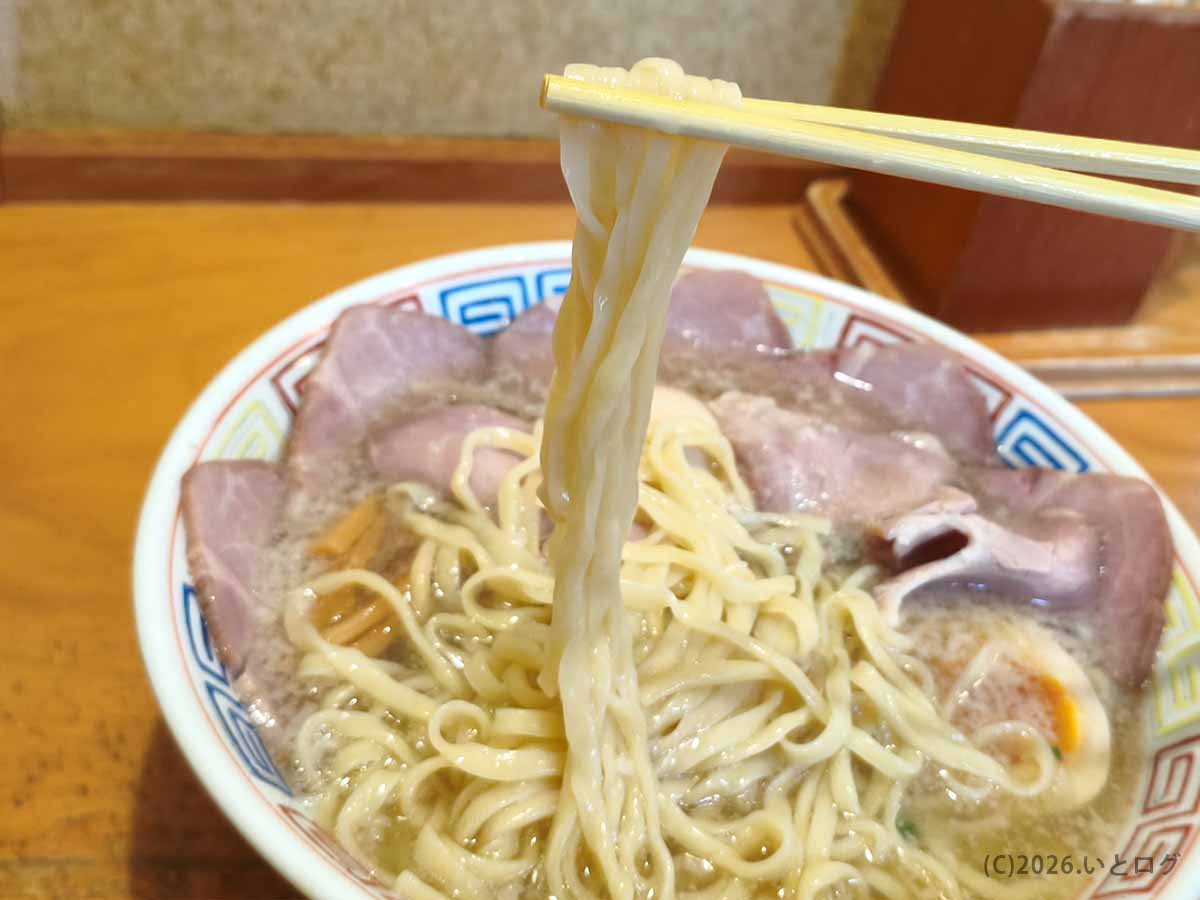 讃岐ラーメン はまんどの平打ち麺を箸で持ち上げた様子。幅広でなめらかな麺がスープをまとい、うどん県らしい個性を感じる一杯。