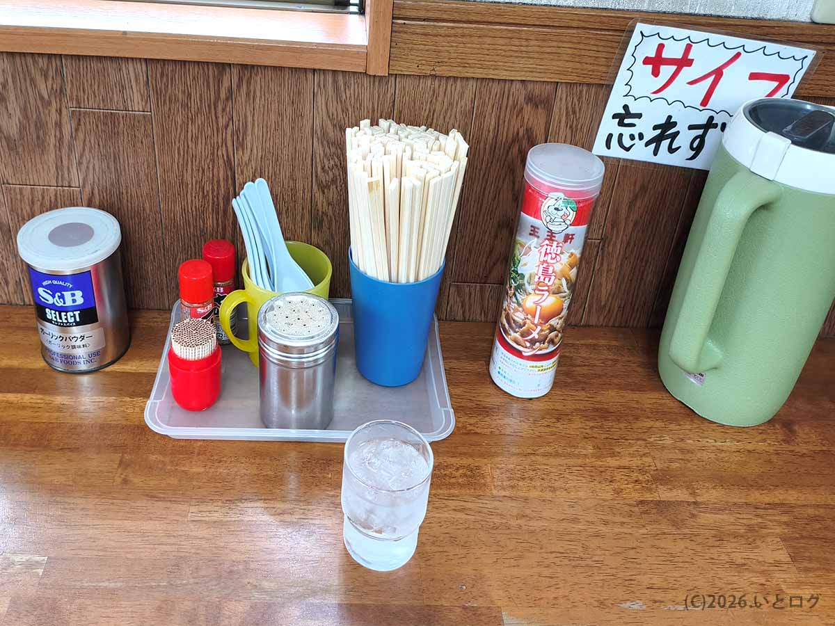 徳島県板野郡藍住町の支那そば 王王軒 本店の卓上に置かれた調味料、箸、レンゲ、徳島ラーメンスープ缶の様子