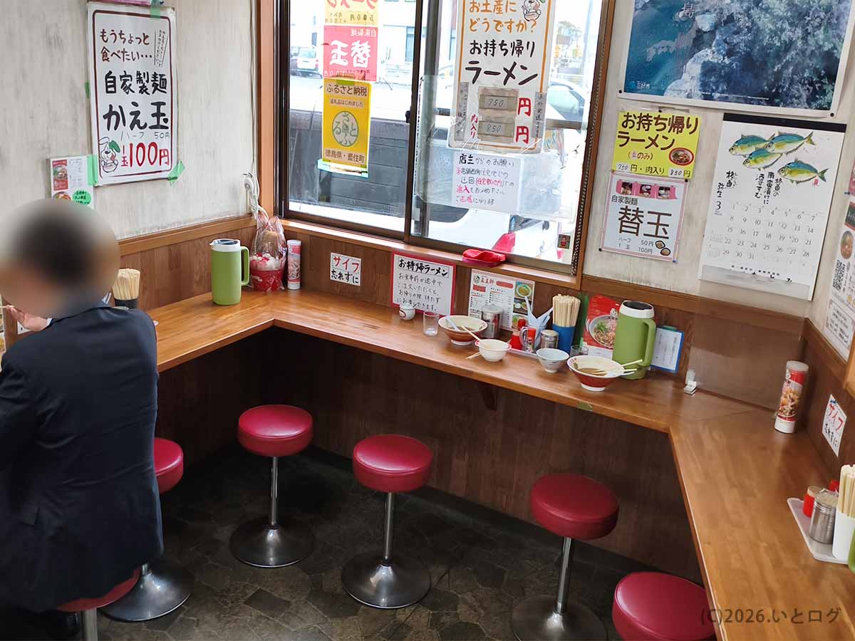 徳島県板野郡藍住町にある王王軒 本店のカウンター席、替玉や持ち帰りラーメンの案内が掲示された店内風景