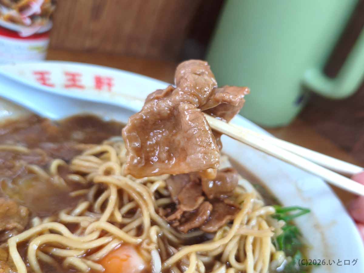 王王軒 本店の徳島ラーメンにのった甘辛い肉を箸で持ち上げた様子
