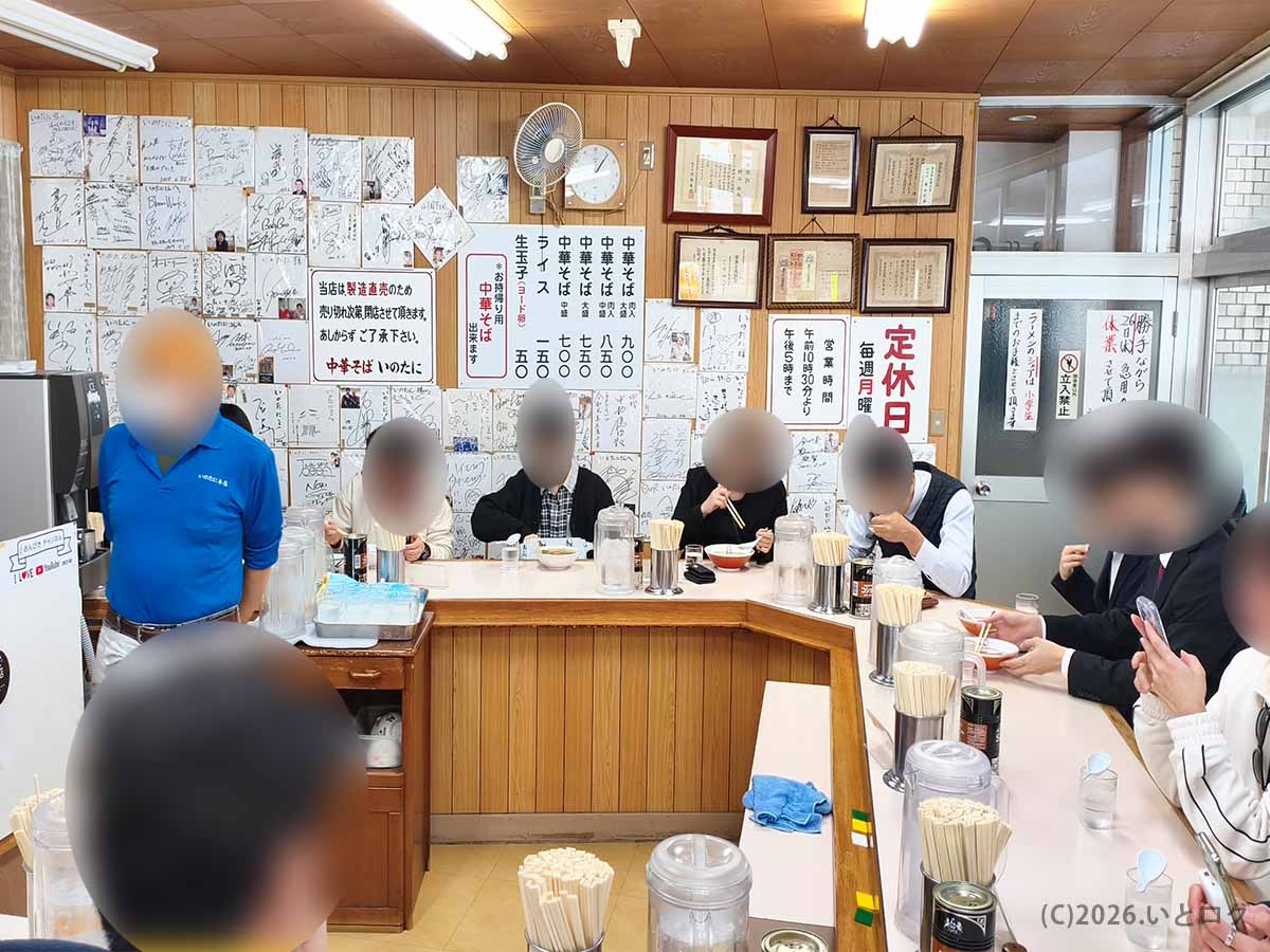 中華そば いのたに 本店の店内風景。カウンター席を中心に多くの客が徳島ラーメンを食べており、壁にはサイン色紙やメニューが並ぶ。