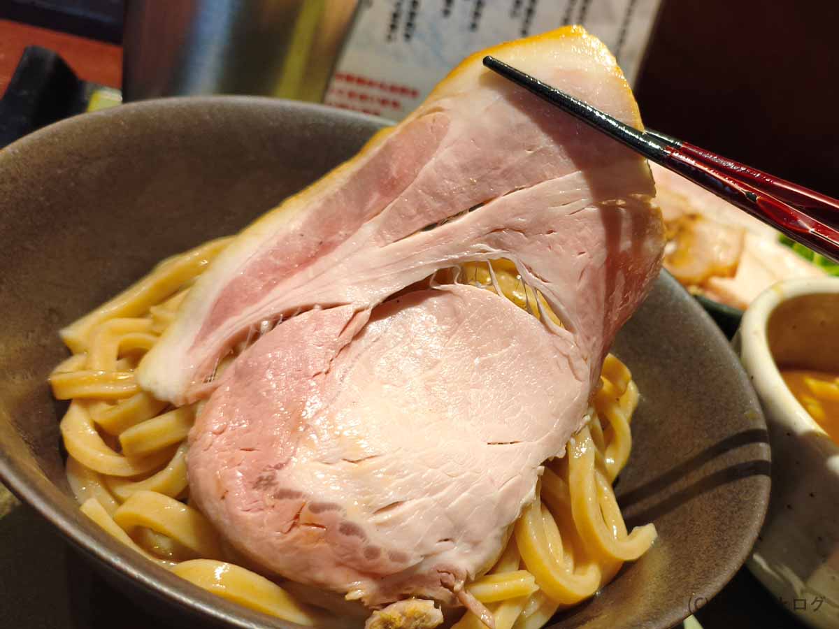 自家製極太麺の上に盛り付けられた、淡いピンク色の大判チャーシュー