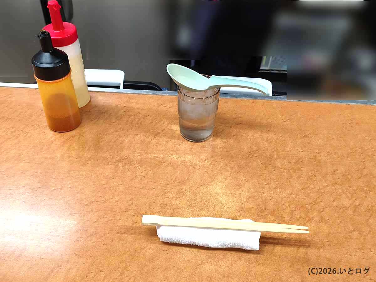 歴史を刻め 六甲道のカウンターに置かれた卓上調味料、水、レンゲ、箸