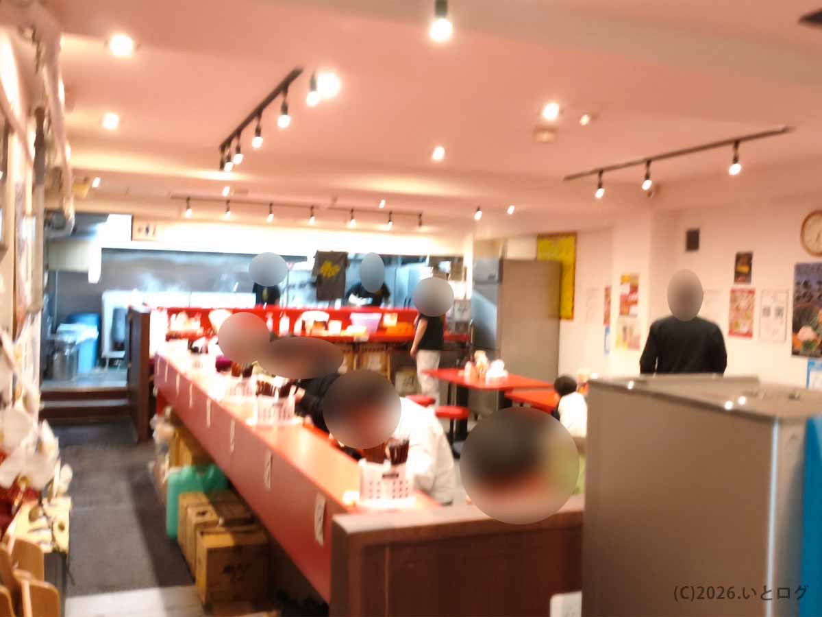 平塚駅近くにある家系ラーメン店「とらきち家」の店内。赤いカウンター席とテーブル席が並ぶ広々とした空間