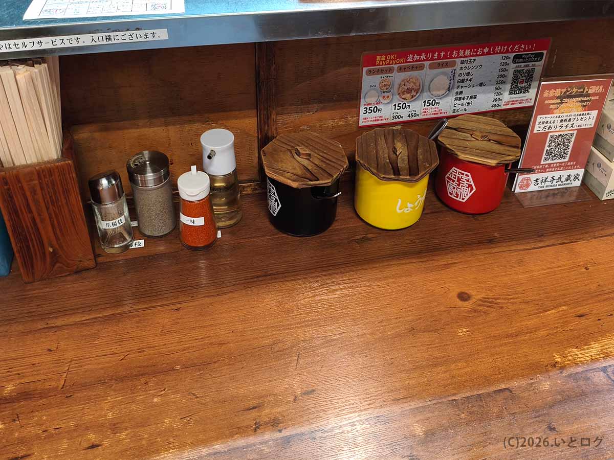 吉祥寺武蔵家 本店のカウンターに置かれた卓上調味料。ニンニクやショウガ、辛味調味料、コショウなどが用意されている