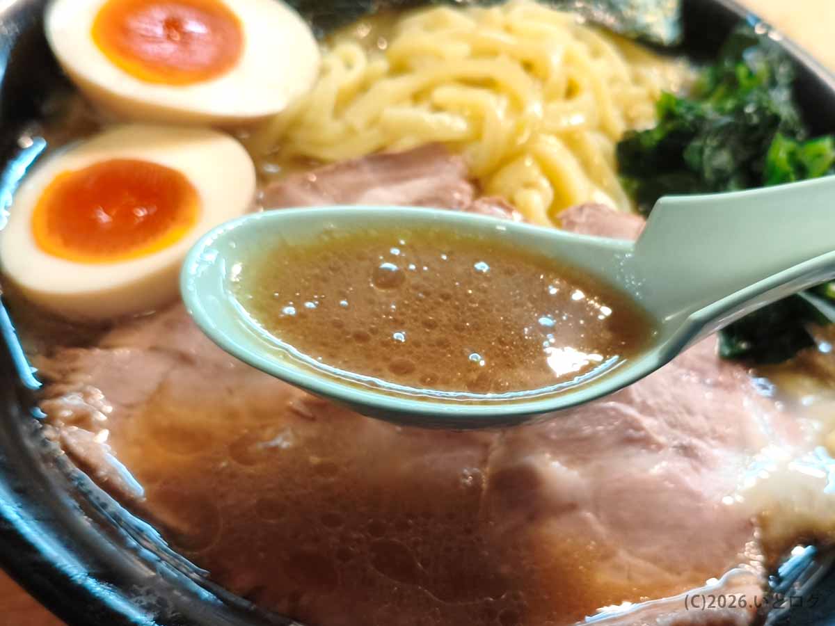 吉祥寺武蔵家 本店の家系ラーメン。レンゲですくった茶褐色の豚骨醤油スープと、チャーシュー、味付玉子、太麺が見える