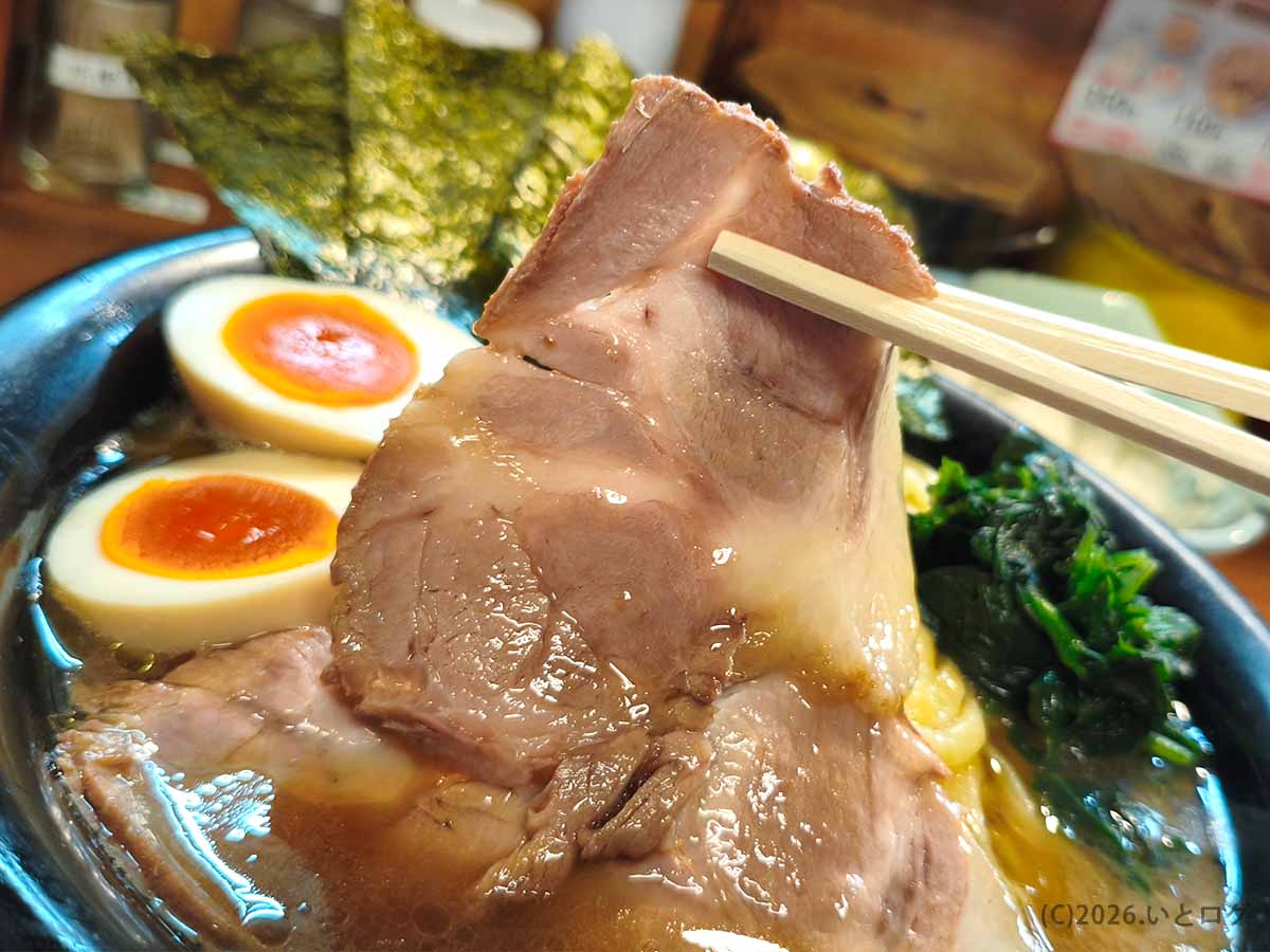 吉祥寺武蔵家 本店のラーメンに盛られた大判チャーシューを箸で持ち上げた様子。薄切りでしっとりとした肉質が伝わる