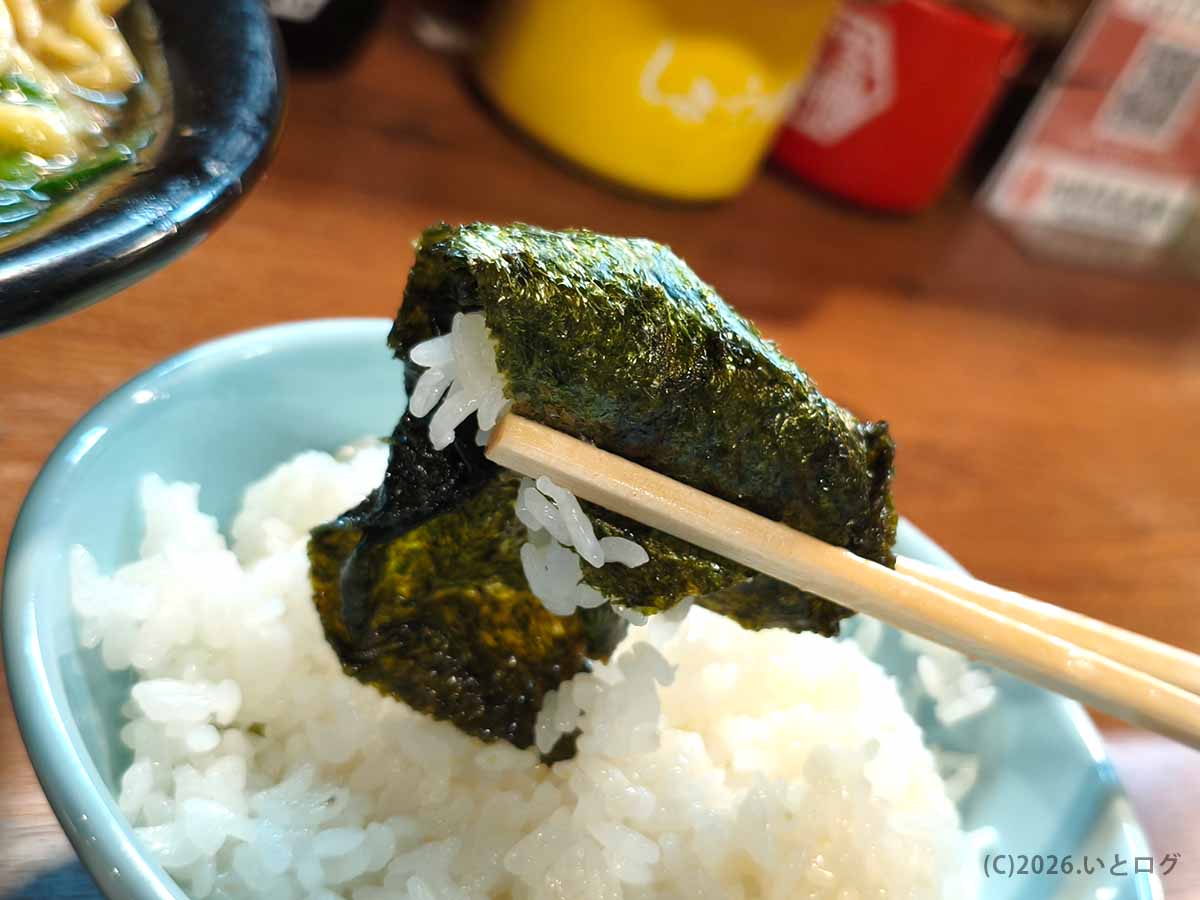 吉祥寺武蔵家 本店のライスを、豚骨醤油スープを吸った海苔で巻いて箸で持ち上げた様子