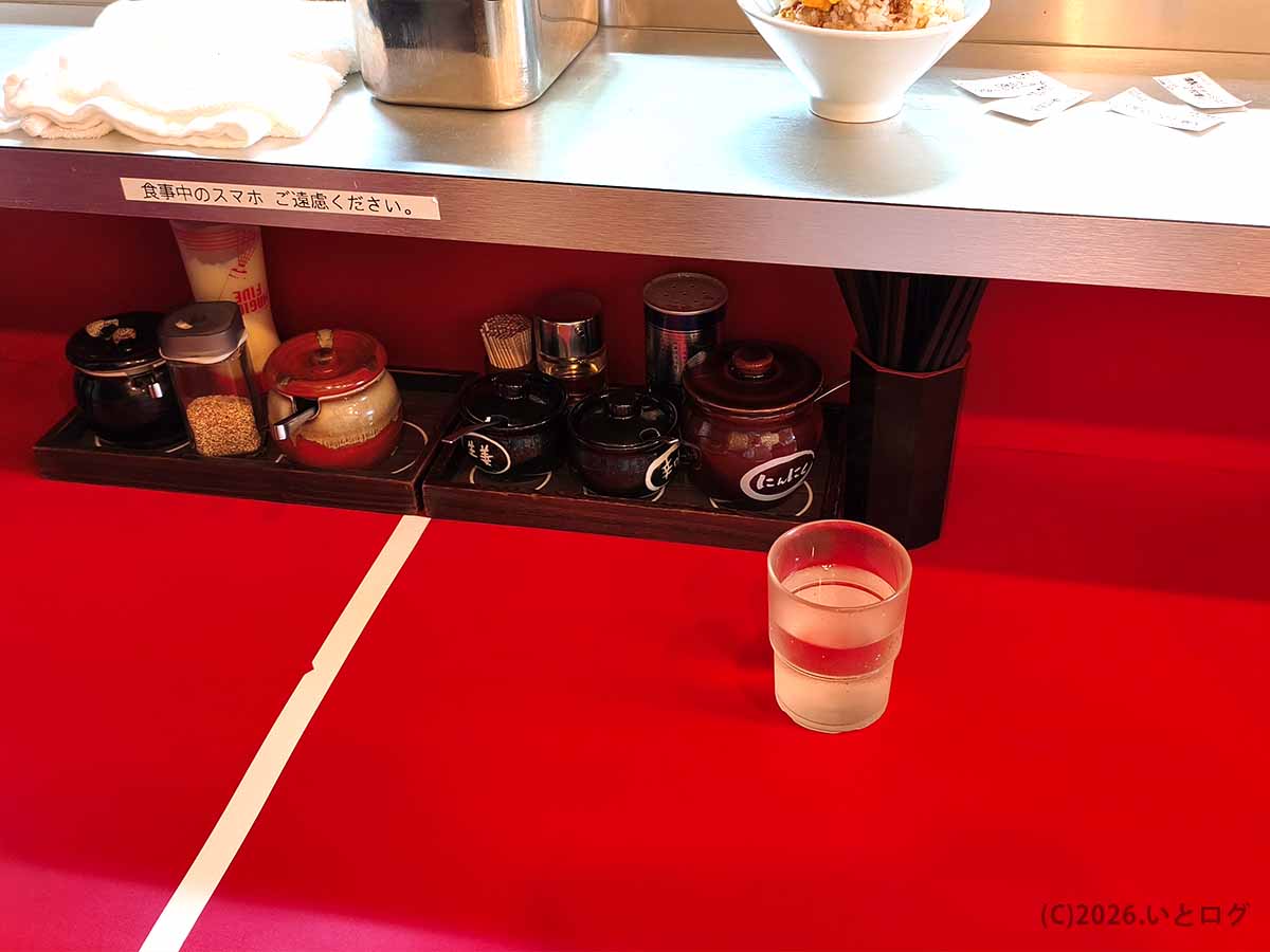 多摩センター近くにある「たま家 多摩本店」の赤いカウンター席を中心とした店内