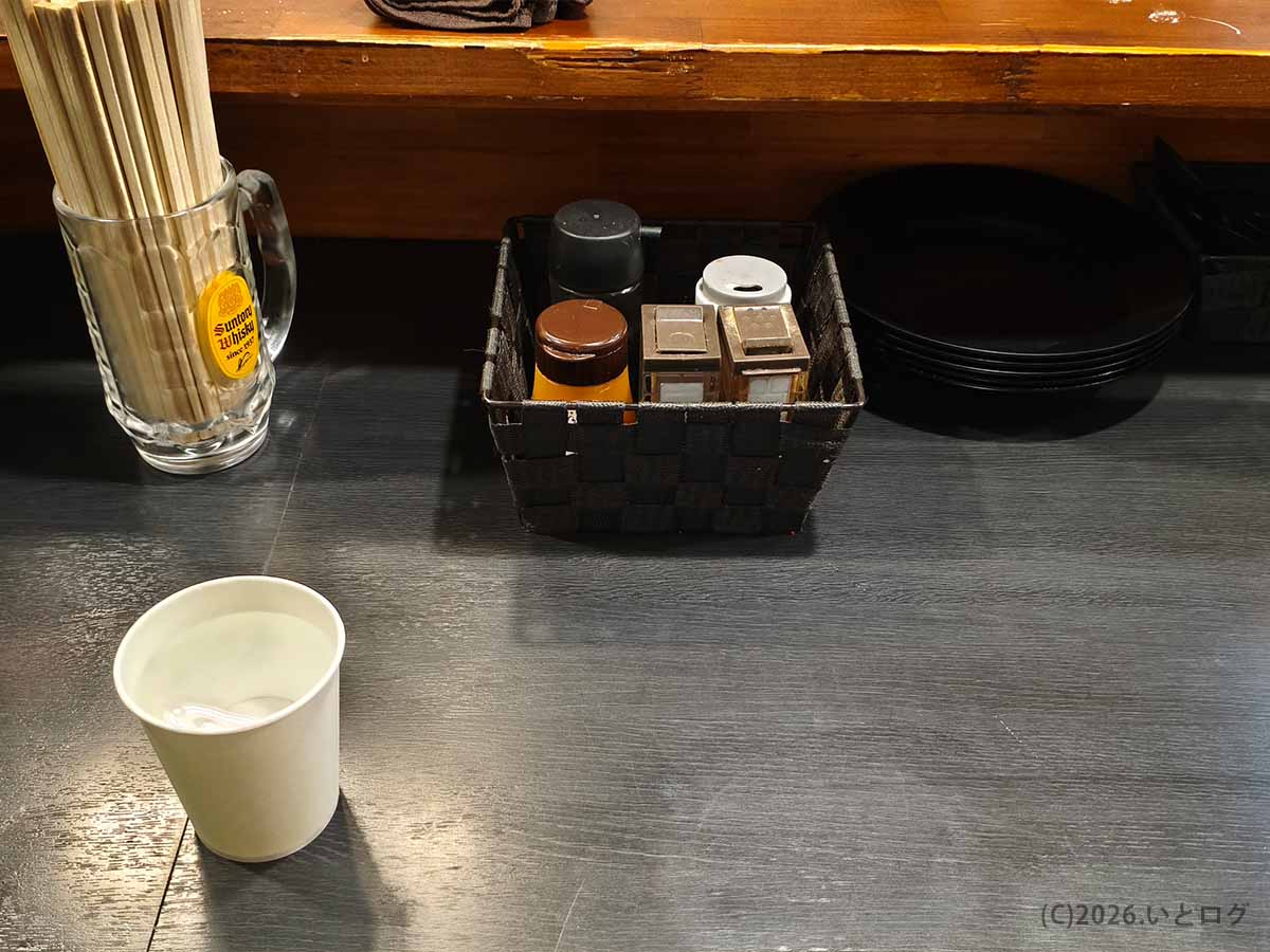 自家製麺No11大山店のカウンターに置かれた箸、水、卓上調味料、取り皿