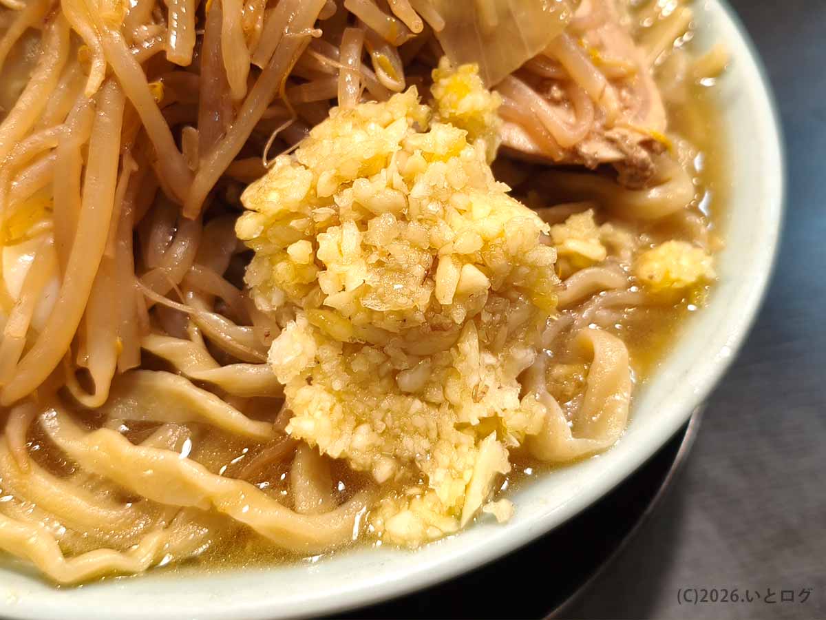 自家製麺No11のラーメンにコールで追加した刻みニンニク。クタ野菜と極太麺の上にたっぷり盛られている