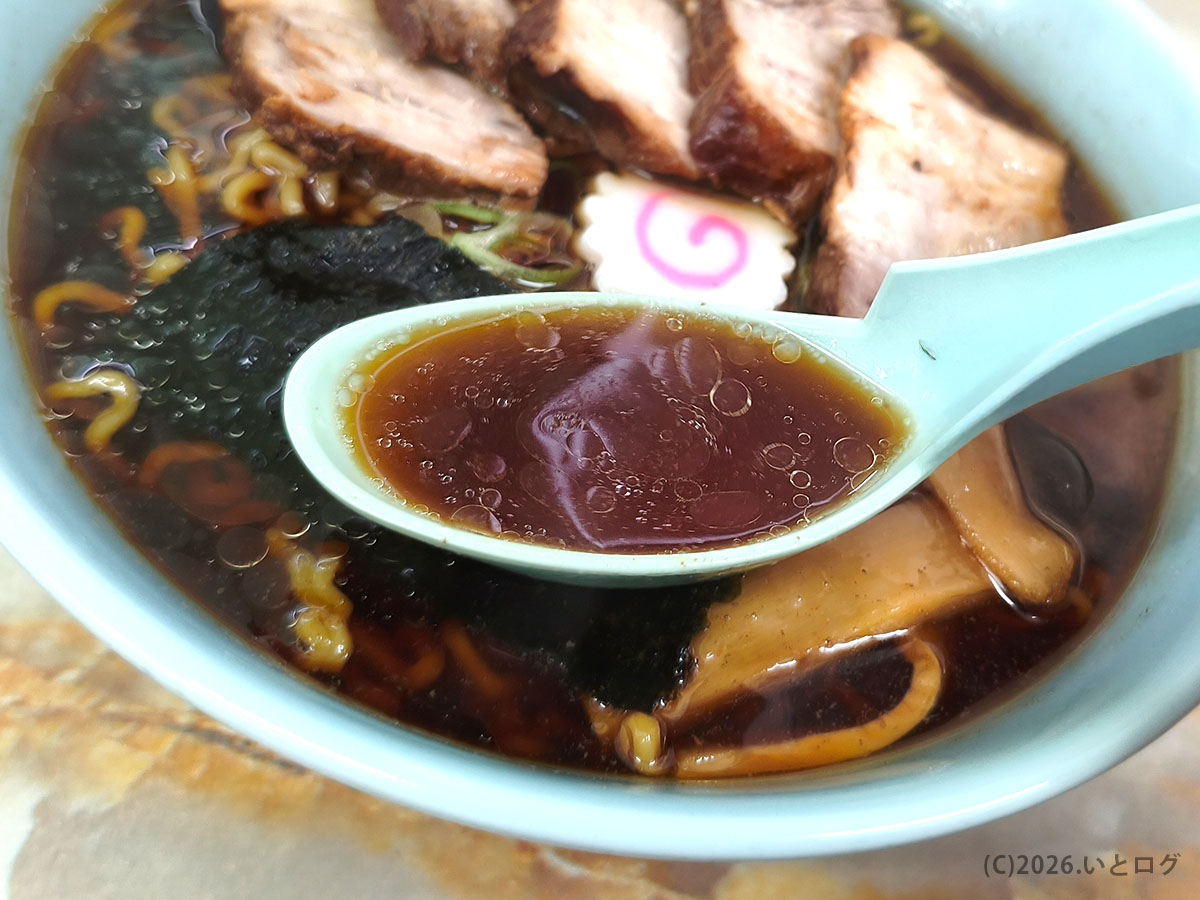 みどりや食堂のラーメンスープをレンゲですくう様子（韮崎・山梨の食堂）