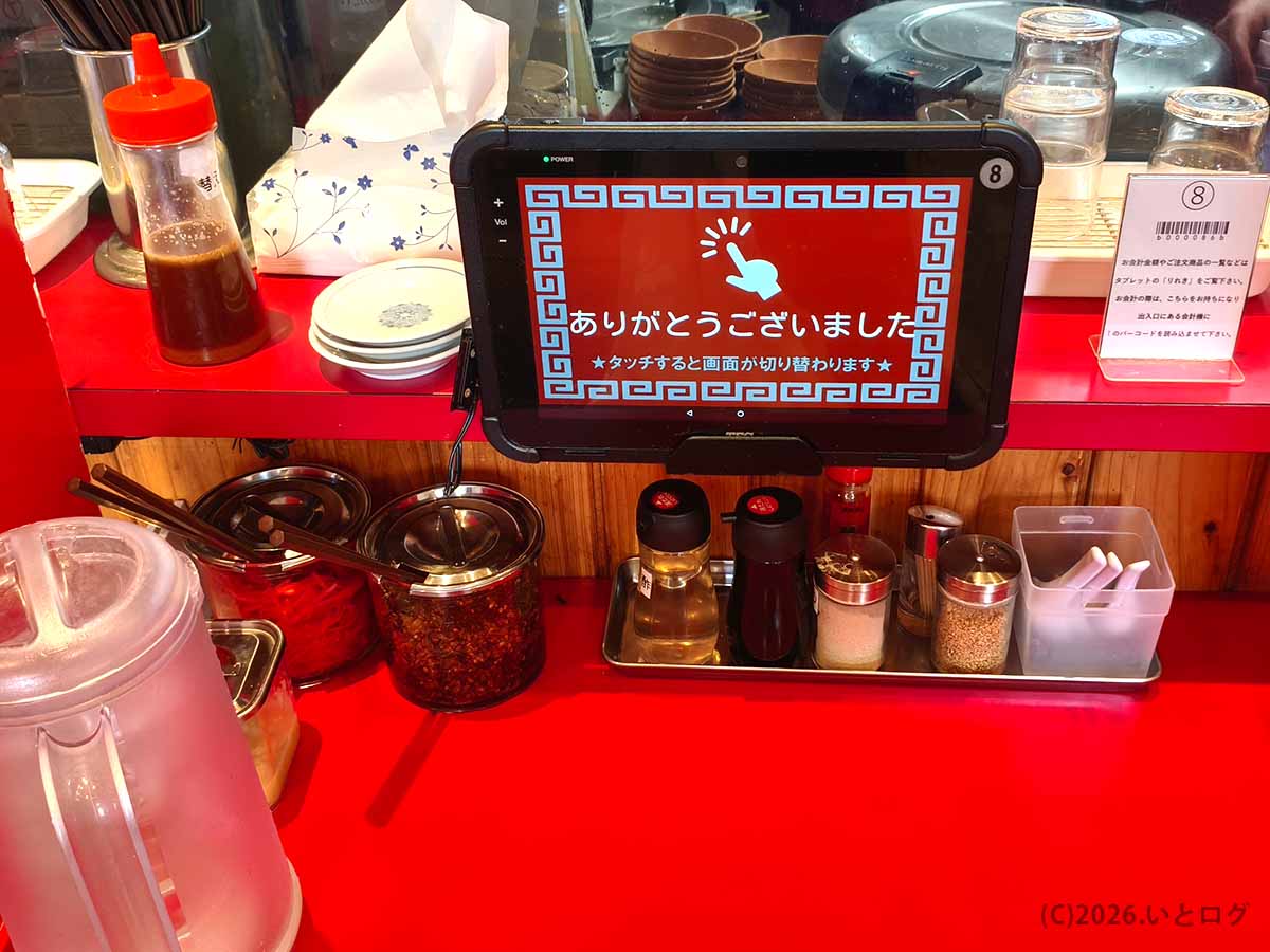 都城のラーメンいってつで使用する注文用タブレットと、紅生姜や辛子高菜などが並ぶ卓上調味料