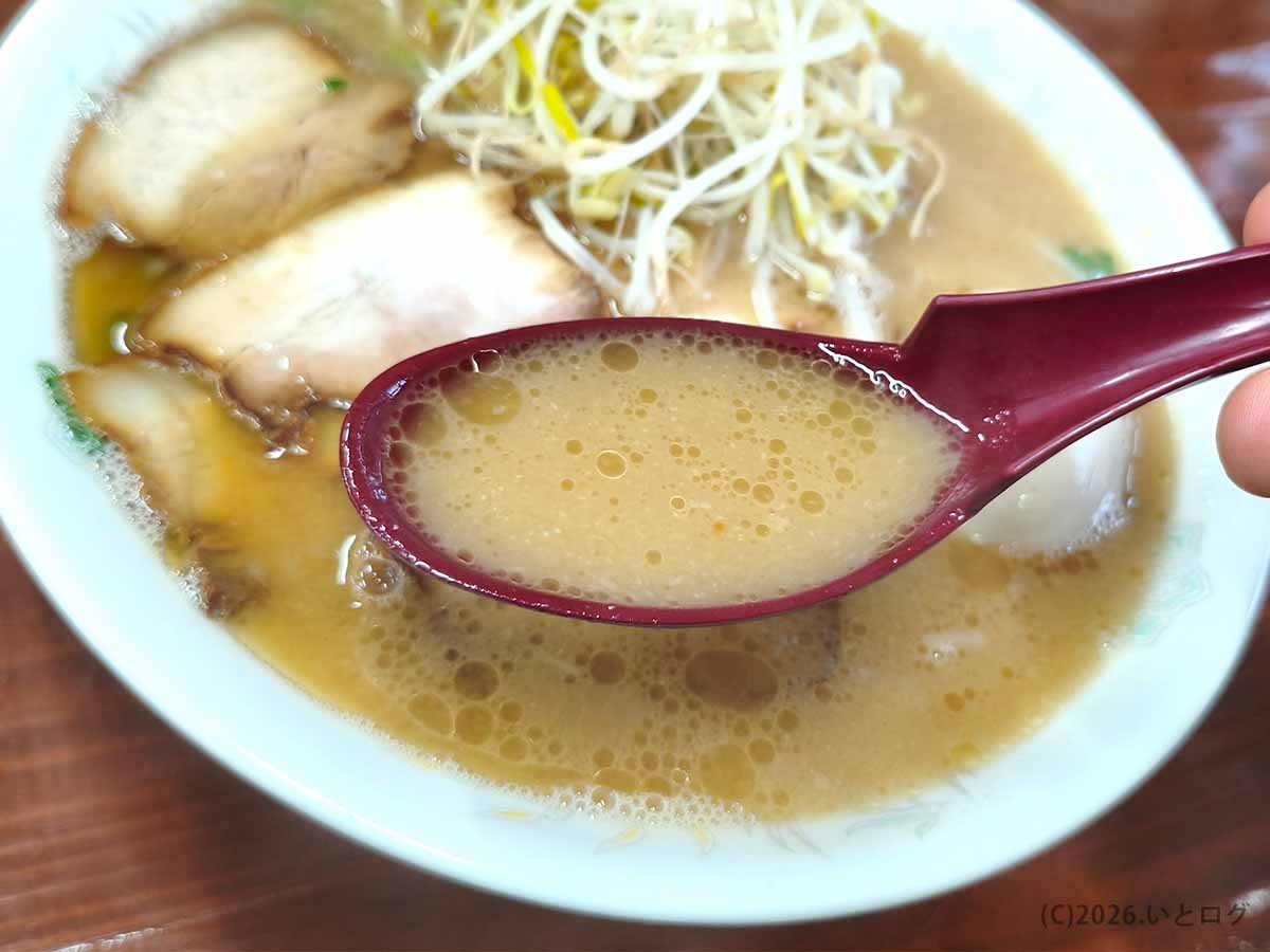 ラーメン洋の豚骨スープをレンゲですくった様子。細かな脂が浮かぶコクのある宮崎ラーメンのスープ