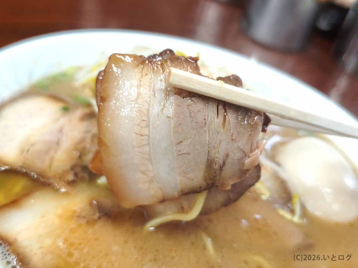 ラーメン洋のチャーシューを箸で持ち上げた様子。脂身の入った厚みのある豚バラチャーシュー