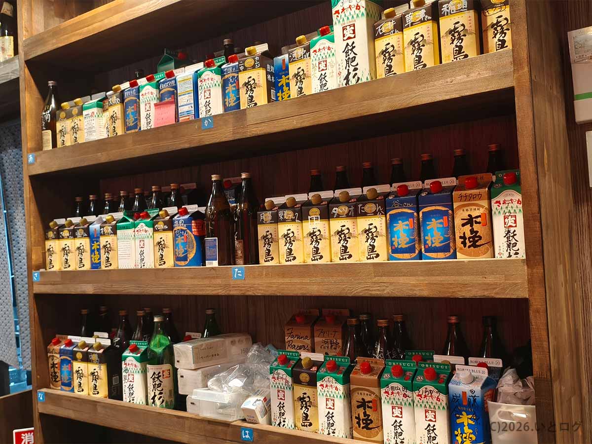丸万焼鳥 支店の店内に並ぶ霧島や木挽など多数の焼酎。宮崎の地鶏料理と一緒に楽しめる