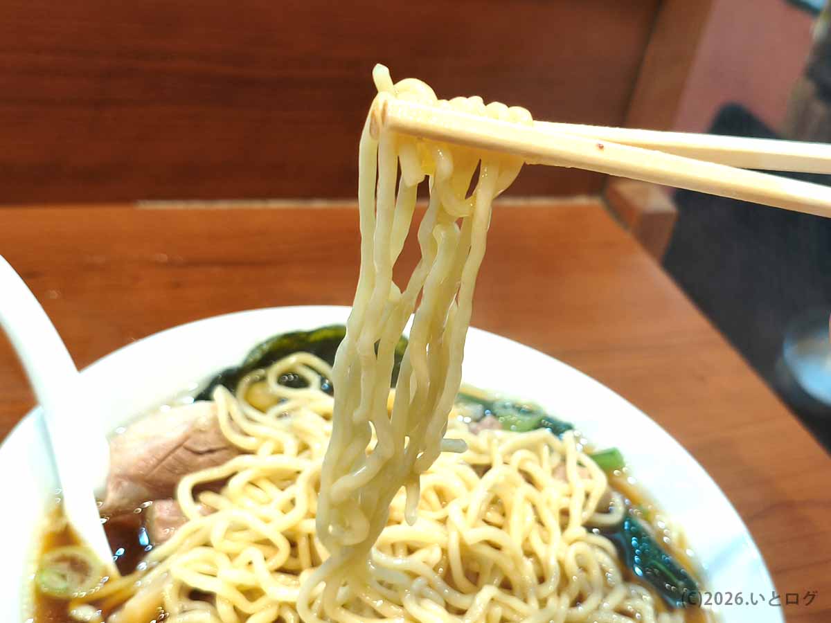 東京らぁめん 西橘店の醤油スープから持ち上げた中太のちぢれ麺